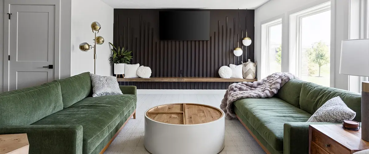 A modern living room with green sofas, black feature wall, and large windows, designed for comfort and style.