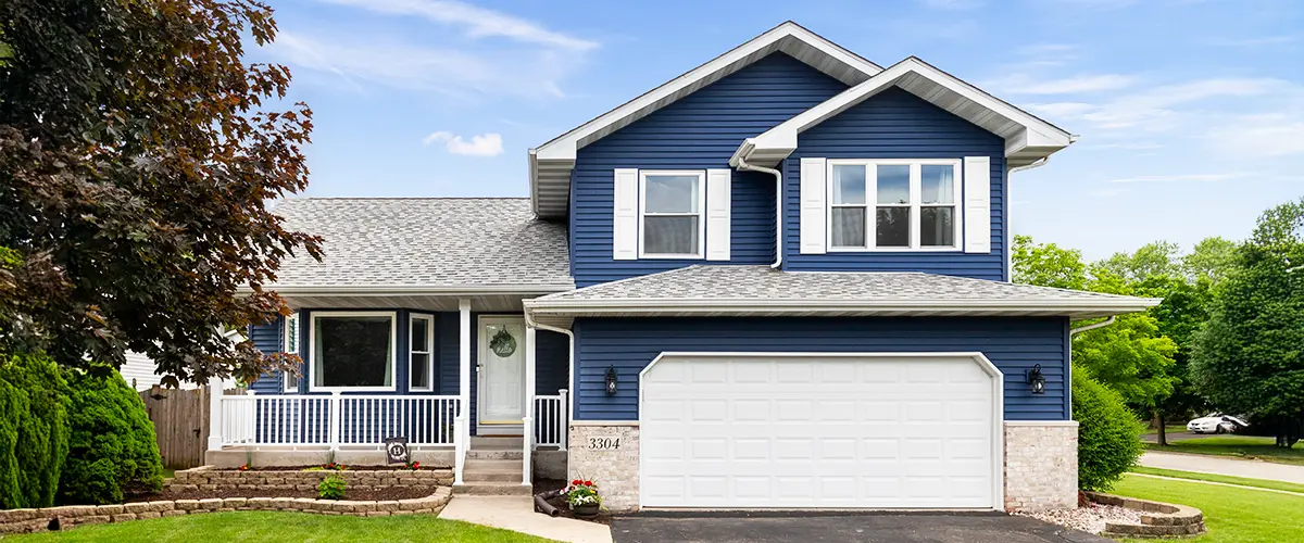 Modern blue two-story home with white trim, a covered porch, and landscaped front yard.