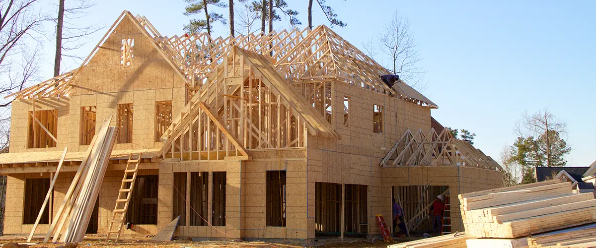 New home construction with wood framing, roof trusses, and large windows