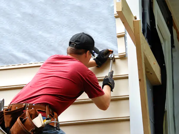 Professional siding installation with a worker securing exterior panels for a durable and energy-efficient home finish.