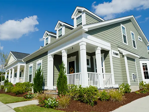 Elegant green craftsman-style home with a spacious front porch, showcasing classic architecture and curb appeal.