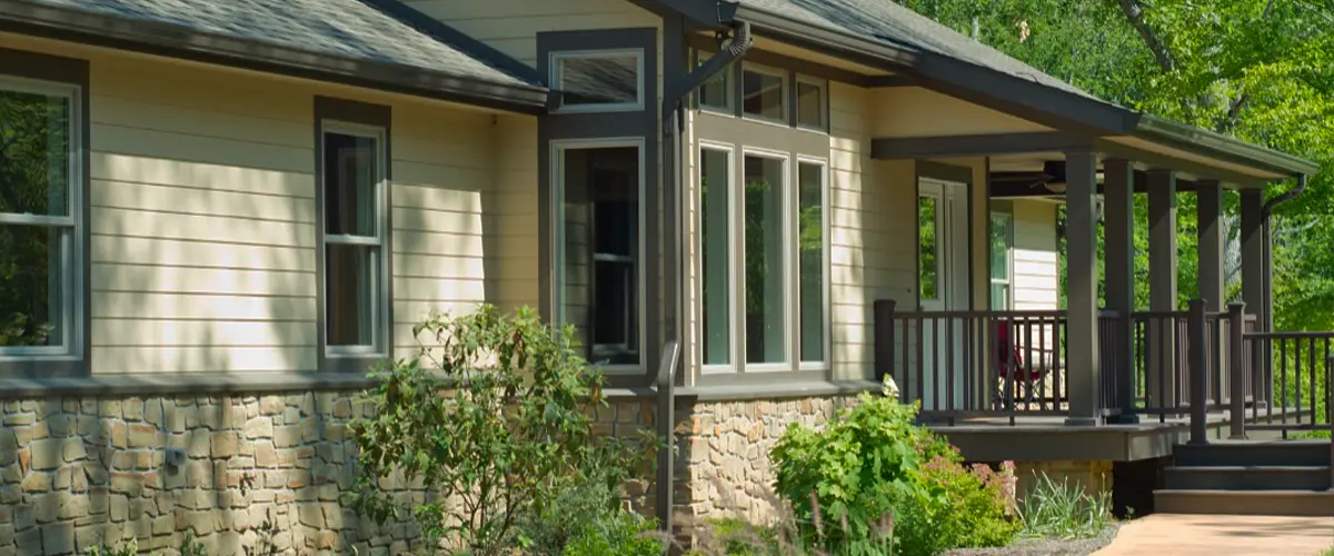 Custom ranch-style home with stone siding, covered porch, and professionally landscaped front yard